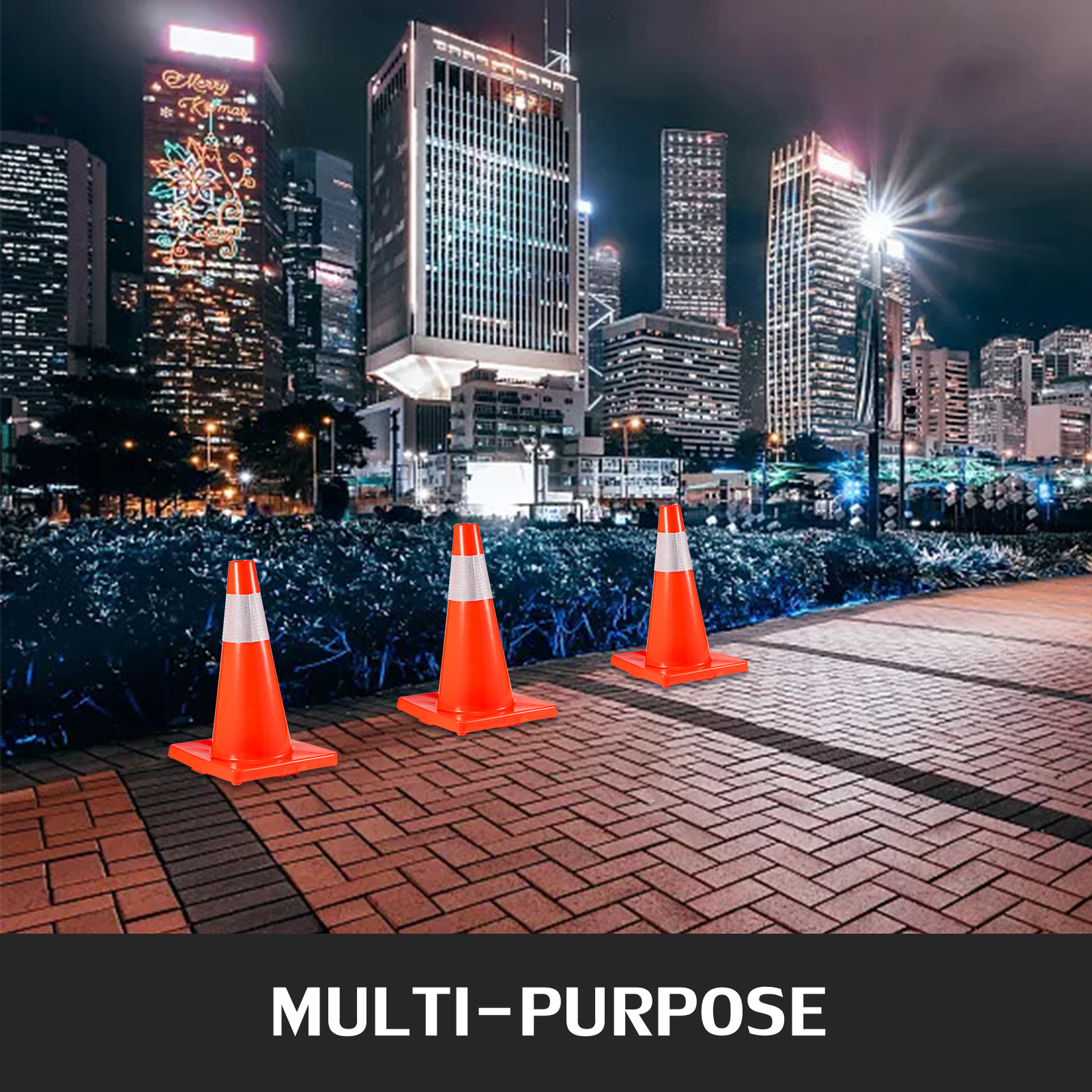 three VEVOR traffic cones on a city sidewalk at night with tall buildings in the background.