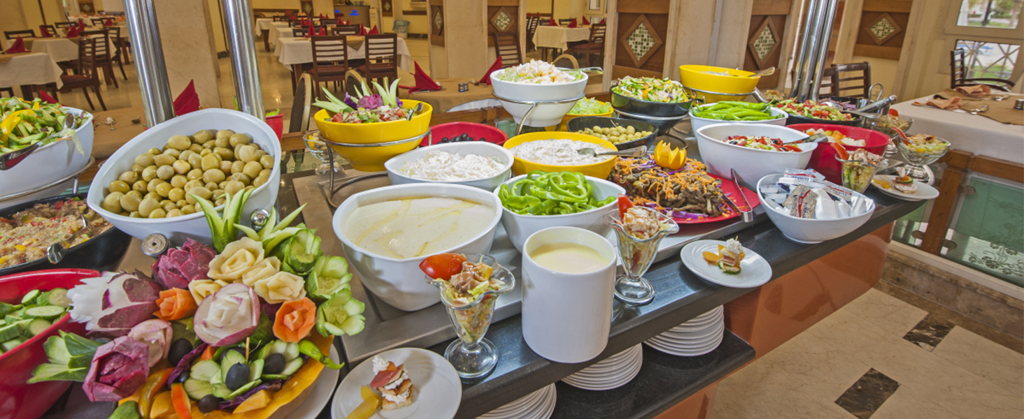 buffet with diverse dishes in bowls, salads, appetizers, and elaborate garnishes, using a VEVOR commercial food warmer.