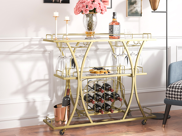 VEVOR bar cart with gold frame, glass shelves, wine rack, and glass holders beside a houndstooth armchair.