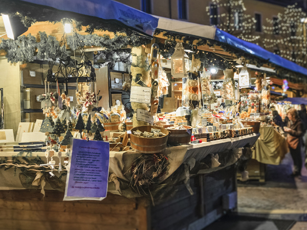 christmas market stall adorned with lights, selling various holiday decorations and treats.