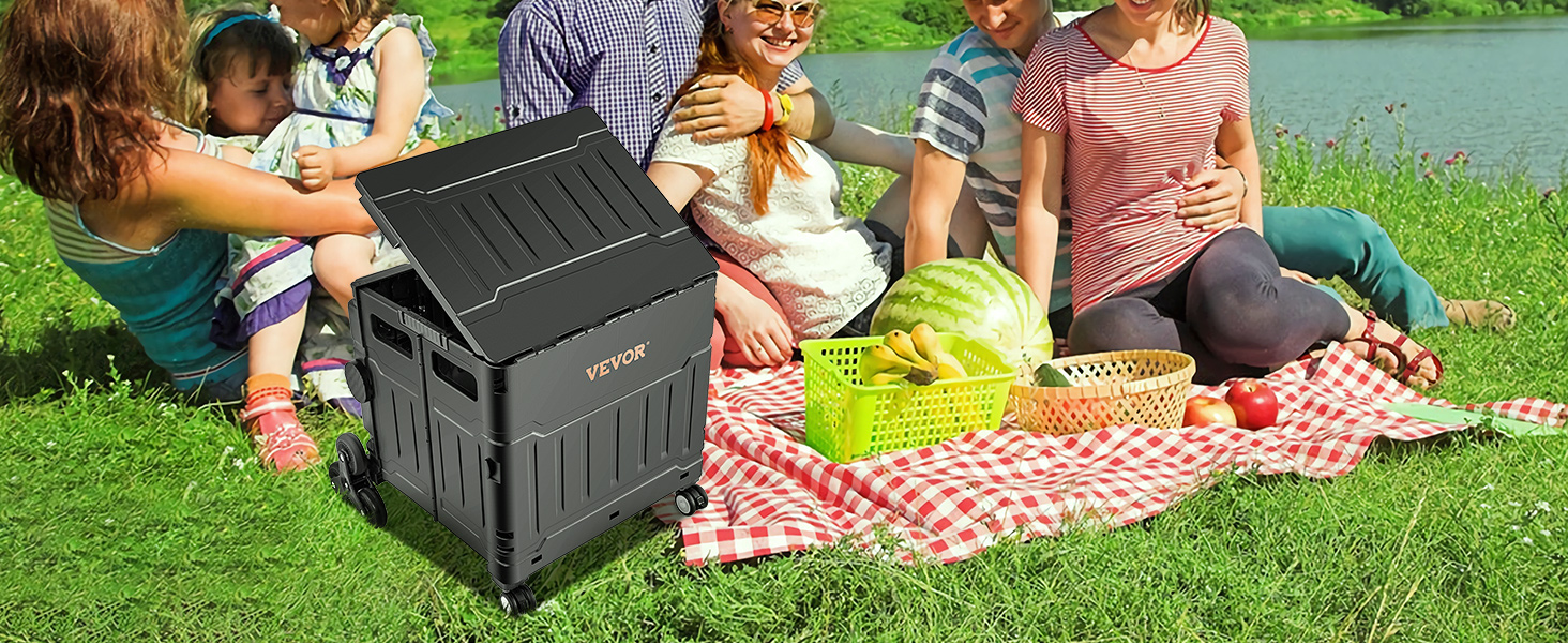 family picnic by a lake with VEVOR stair climbing cart, food baskets, and watermelon on a checkered blanket.