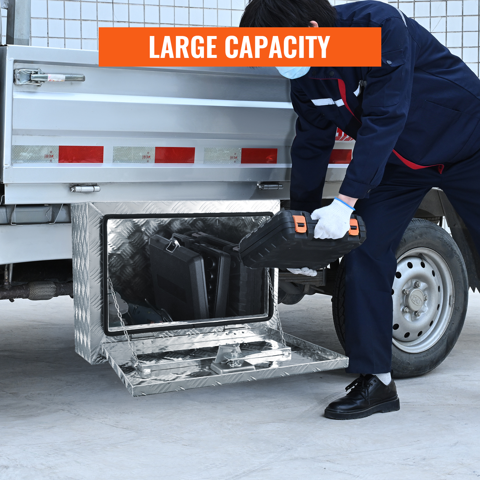 worker storing tool case in a VEVOR underbody truck box, highlighting its large capacity.