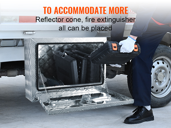 Vīrietis ielādē instrumentus VEVOR kravas automašīnas zemšasijas kastē, kas piestiprināta pie kravas automašīnas.