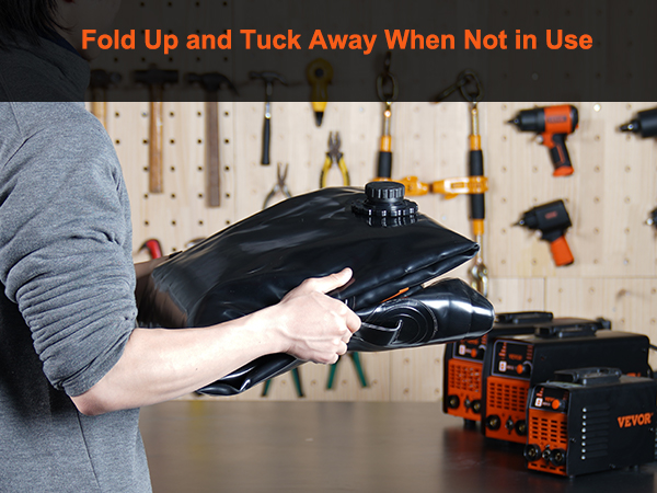 man folding a black VEVOR water tank bladder in a workshop with tools and equipment on shelves.