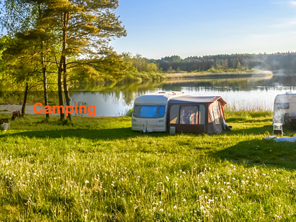 camping site with rvs and trailers beside a scenic lake under a blue sky.