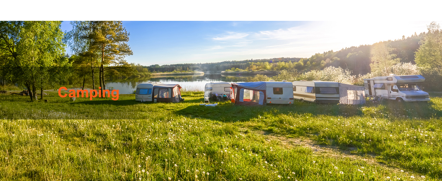 camping site with rvs and trailers beside a scenic lake under a blue sky.
