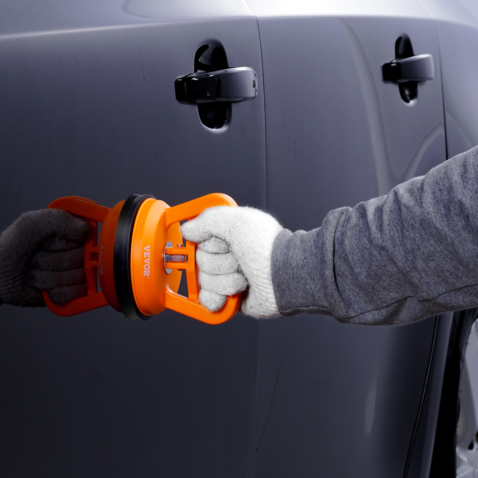 person using the VEVOR dent removal kit on car door with suction cup tool in hand.