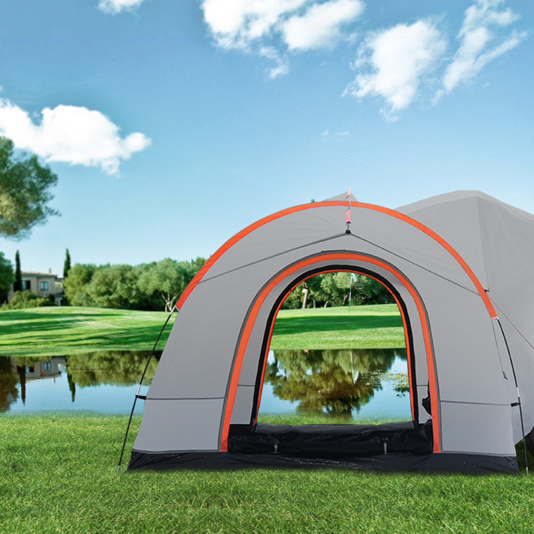 VEVOR suv camping tent setup on green grass near a serene lake under a bright blue sky with scattered clouds.