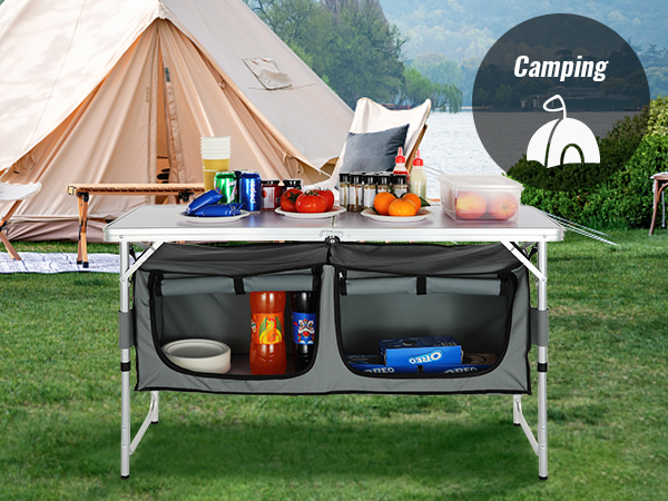 VEVOR camping table with storage pockets and supplies set up in front of a tent near a lake.