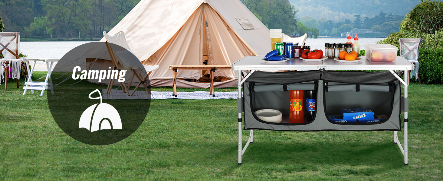VEVOR camping table with storage pockets and supplies set up in front of a tent near a lake.