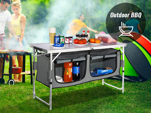 VEVOR camping table set up with drinks and food, next to a tent and bbq in a grassy outdoor setting.