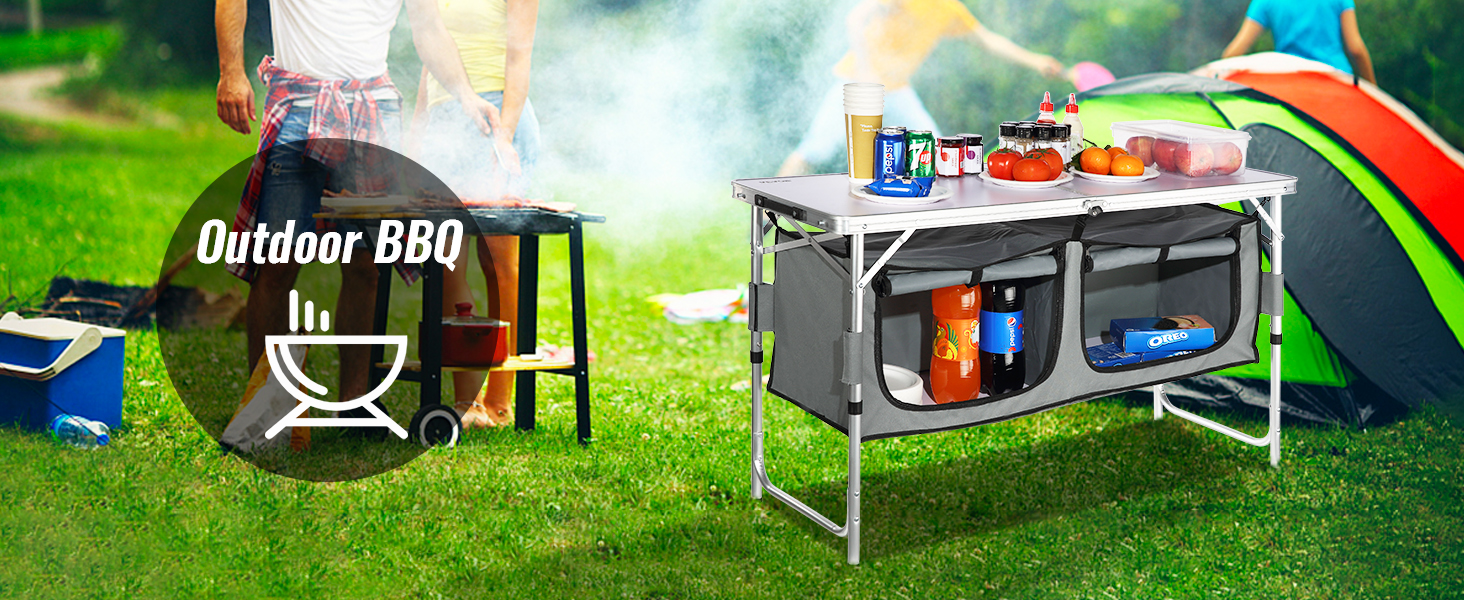 VEVOR camping table set up with drinks and food, next to a tent and bbq in a grassy outdoor setting.
