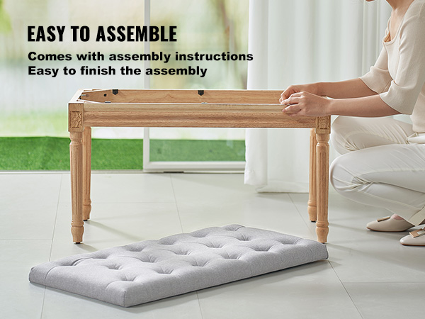 person assembling VEVOR upholstered bench with wooden legs and a gray cushion on a tile floor.