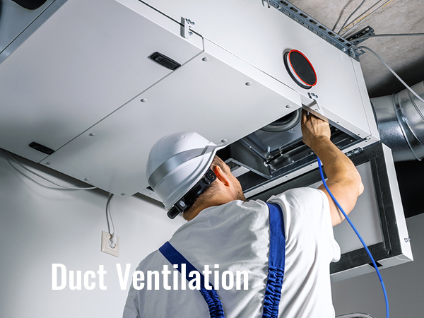 рабочий в каске регулирует систему вентиляции воздуховодов ОВКВ на потолке.