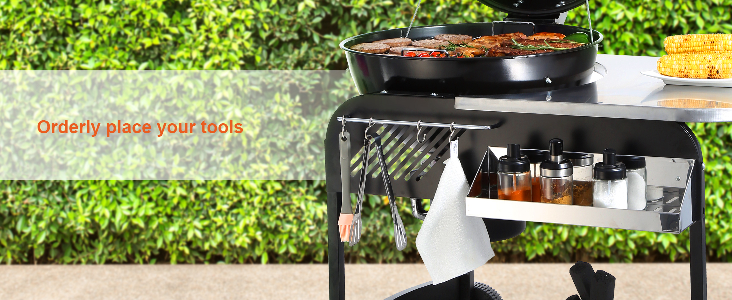 VEVOR charcoal grill with tool hooks, spices, and grilled food against a green hedge backdrop.