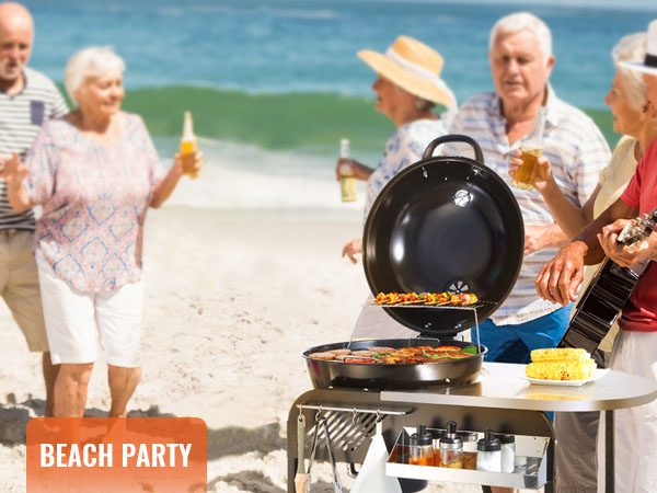 beach party with friends grilling on a VEVOR charcoal grill and enjoying drinks by the shore.