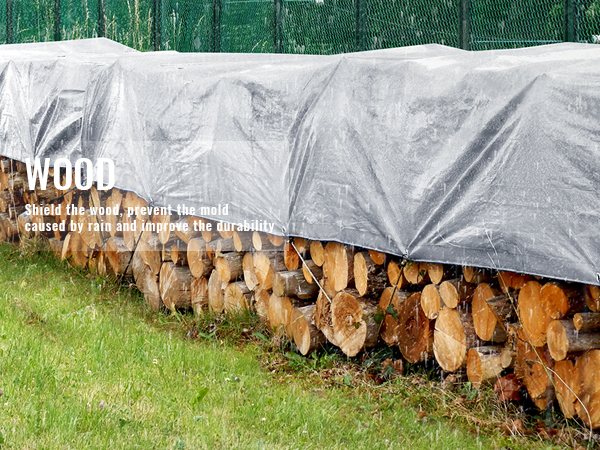 stacked firewood covered by a VEVOR waterproof tarp protecting it from rain in a grassy area.