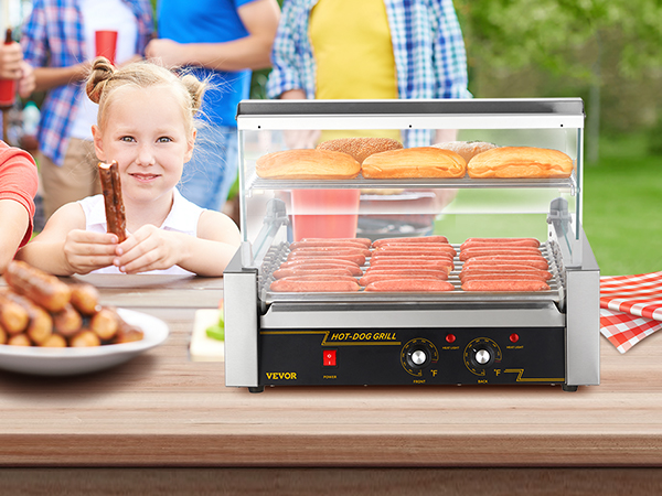 Bērni piknikā bauda hotdogus, priekšplānā grilējot desiņas un maizītes ar VEVOR hotdogu rullīti.
