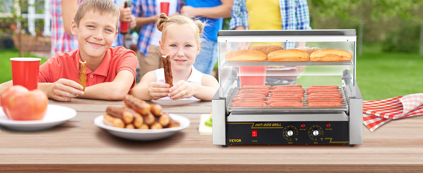 Bērni piknikā bauda hotdogus, priekšplānā grilējot desiņas un maizītes ar VEVOR hotdogu rullīti.