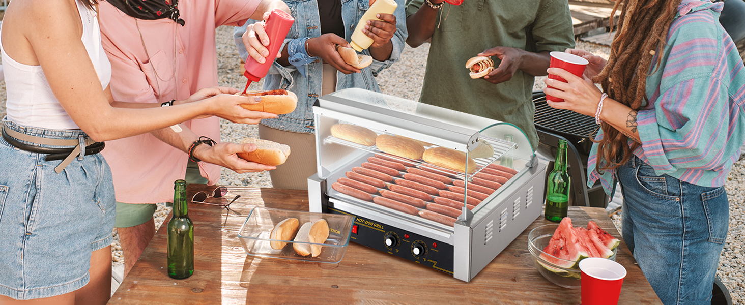 Draugi bauda hotdogus ar VEVOR hotdogu rullīti brīvdabas pulcēšanās laikā.