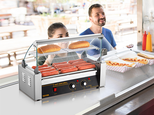 hot dogs and buns on VEVOR hot dog roller in a food stall, with vendor taking orders and condiments nearby.