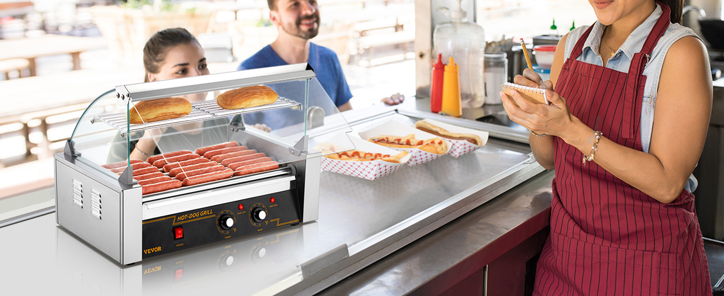 VEVOR hotdogu rullis ēdienu stendā ar gatavotiem hotdogiem, maizītēm uz plaukta un apkalpotāju, kas pieņem pasūtījumus.