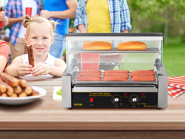 Bērni piknikā ar VEVOR hotdogu rullīti grilē hotdogus un maizītes uz koka galda ar ēdienu.