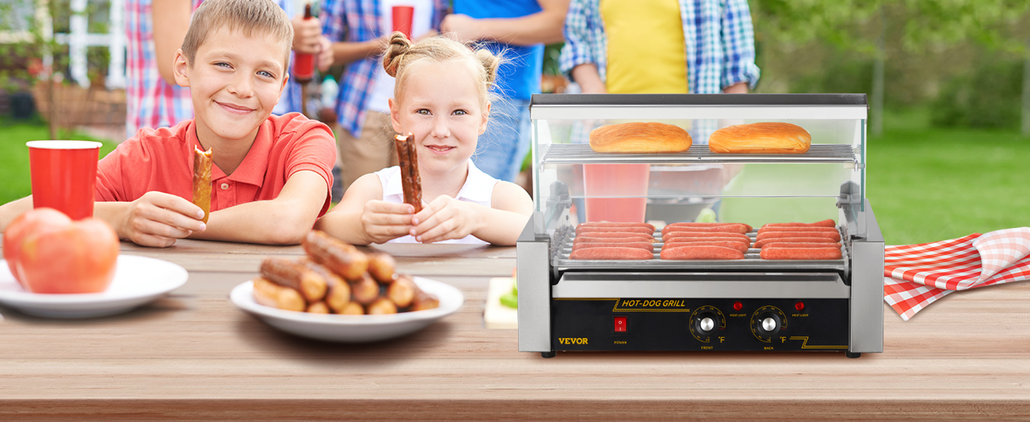 Bērni piknikā ar VEVOR hotdogu rullīti grilē hotdogus un maizītes uz koka galda ar ēdienu.