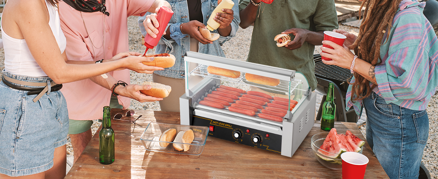 Draugi bauda bārbekjū pagalmā ar VEVOR hotdogu rullīti, hotdogiem, maizītēm un garšvielām uz galda.