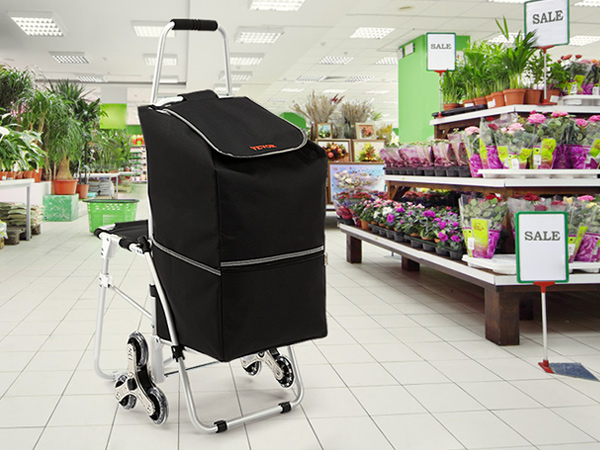VEVOR stair climbing cart in a garden center with flower shelves and sale signs.