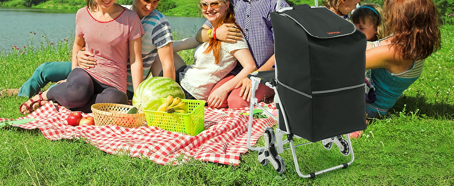 picnic by the lake with picnic supplies, VEVOR stair climbing cart, and fruits on checked blanket.
