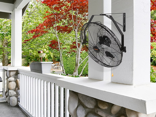 VEVOR wall mount fan on a porch with green and red foliage in the background.