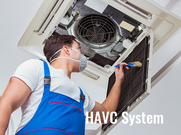 Tehniķis zilā kombinezonā tīra HVAC sistēmas filtru ar otu apkopes vajadzībām.