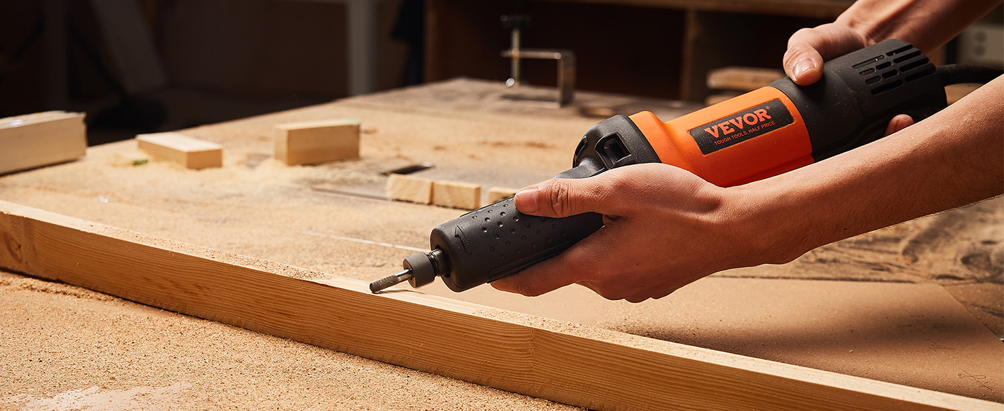 carpenter using VEVOR die grinder to sand a wooden plank in a workshop surrounded by tools and wood shavings.
