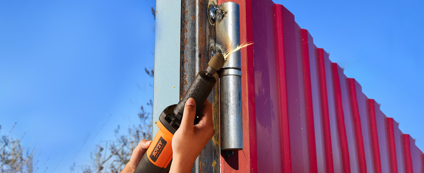 person using VEVOR die grinder to grind a metal piece attached to red metal panels on a sunny day.