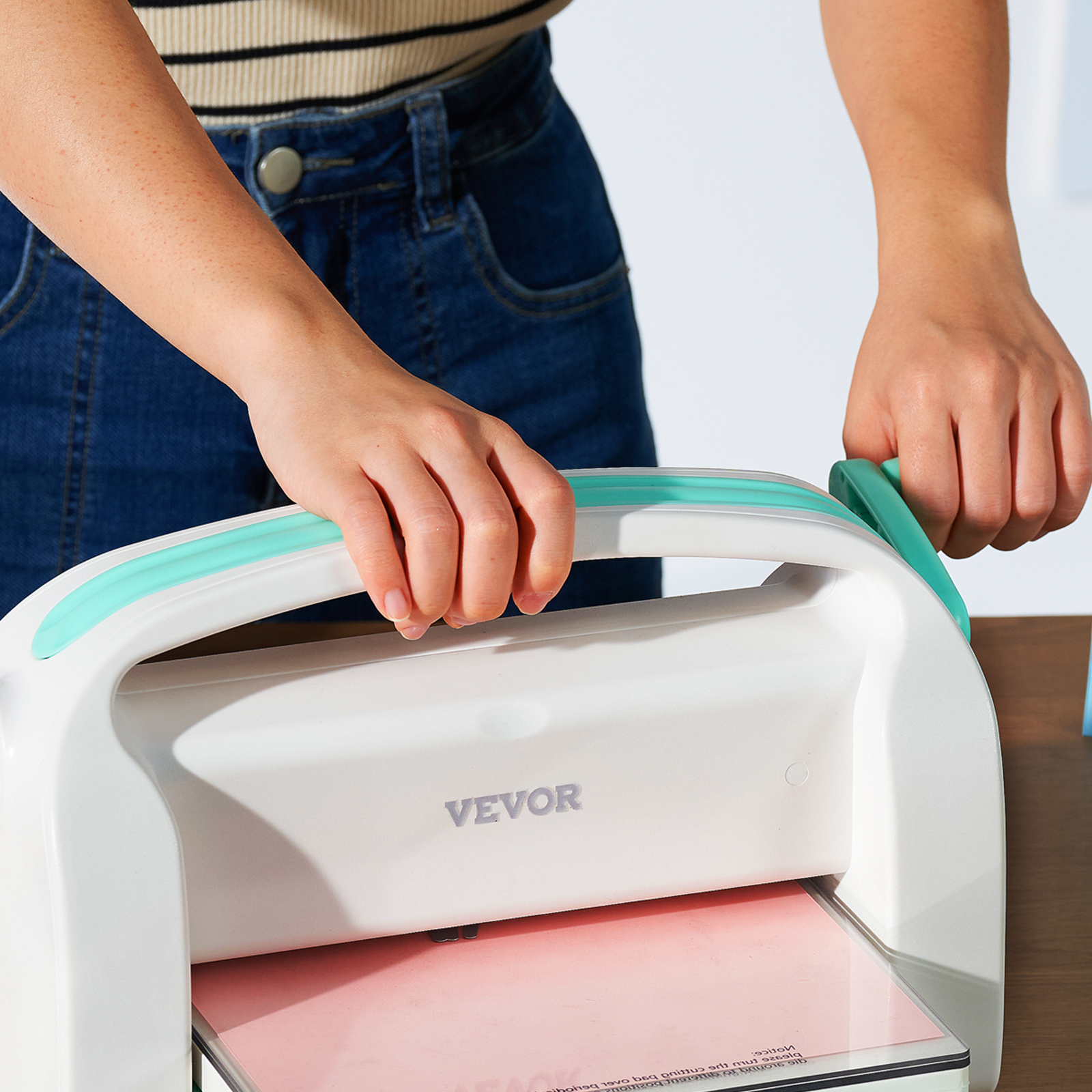 person using VEVOR die cutting machine on a desk with hands holding the handles.