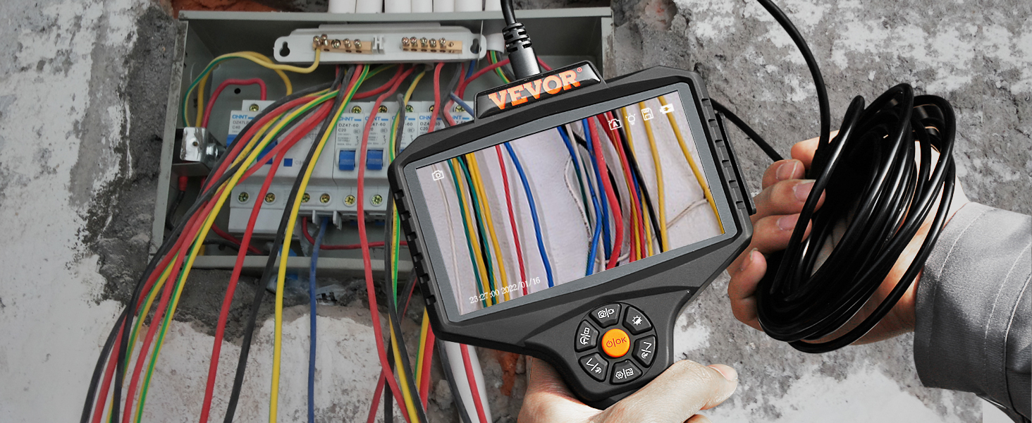 käsi kasutades VEVOR triple objektiivi borescope, et kontrollida elektrijuhtmete seina sees.