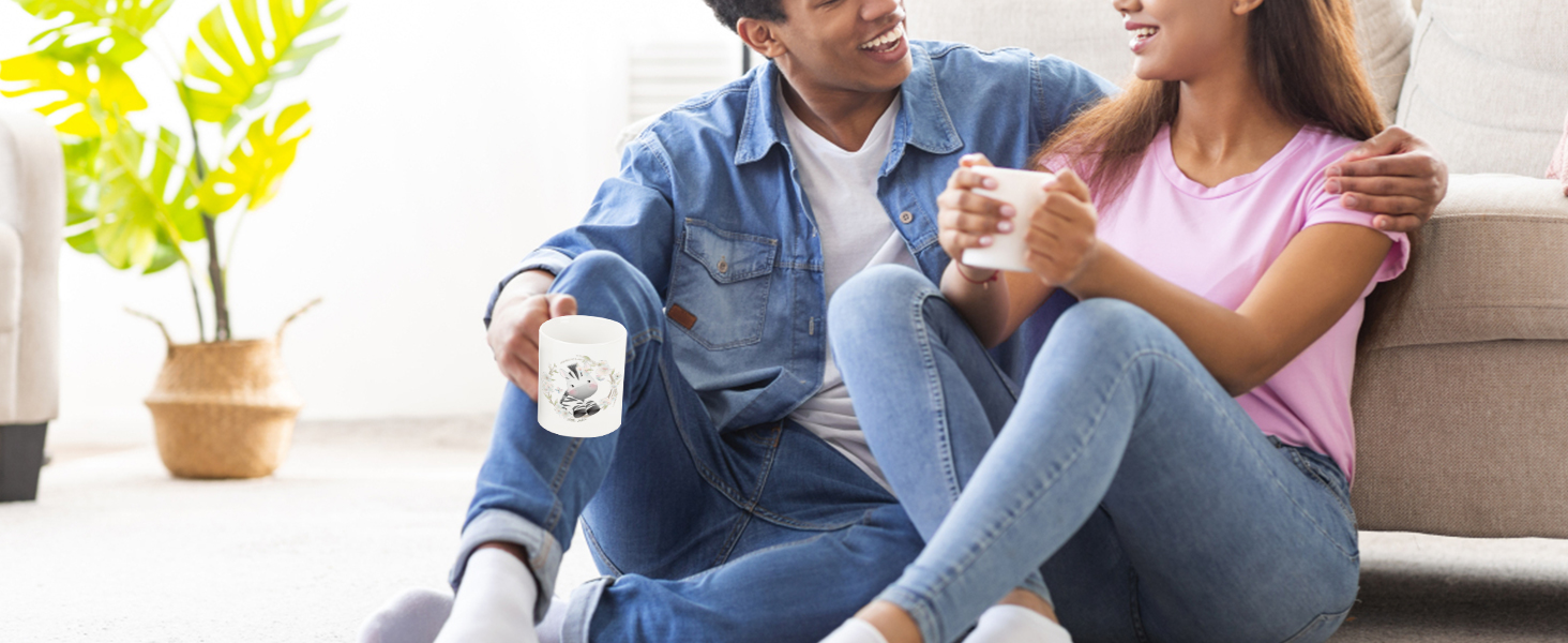 pora sėdi ant grindų ir mėgaujasi kava, atskleis užsakymą puodeliai pagaminti su VEVOR masažuoklis šilumos spaudos.