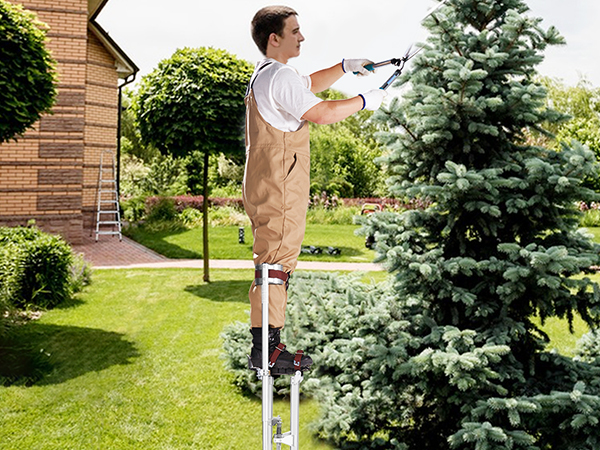 садовник использует гипсокартонные сваи VEVOR для обрезки дерева на пышном зеленом заднем дворе кирпичного дома.