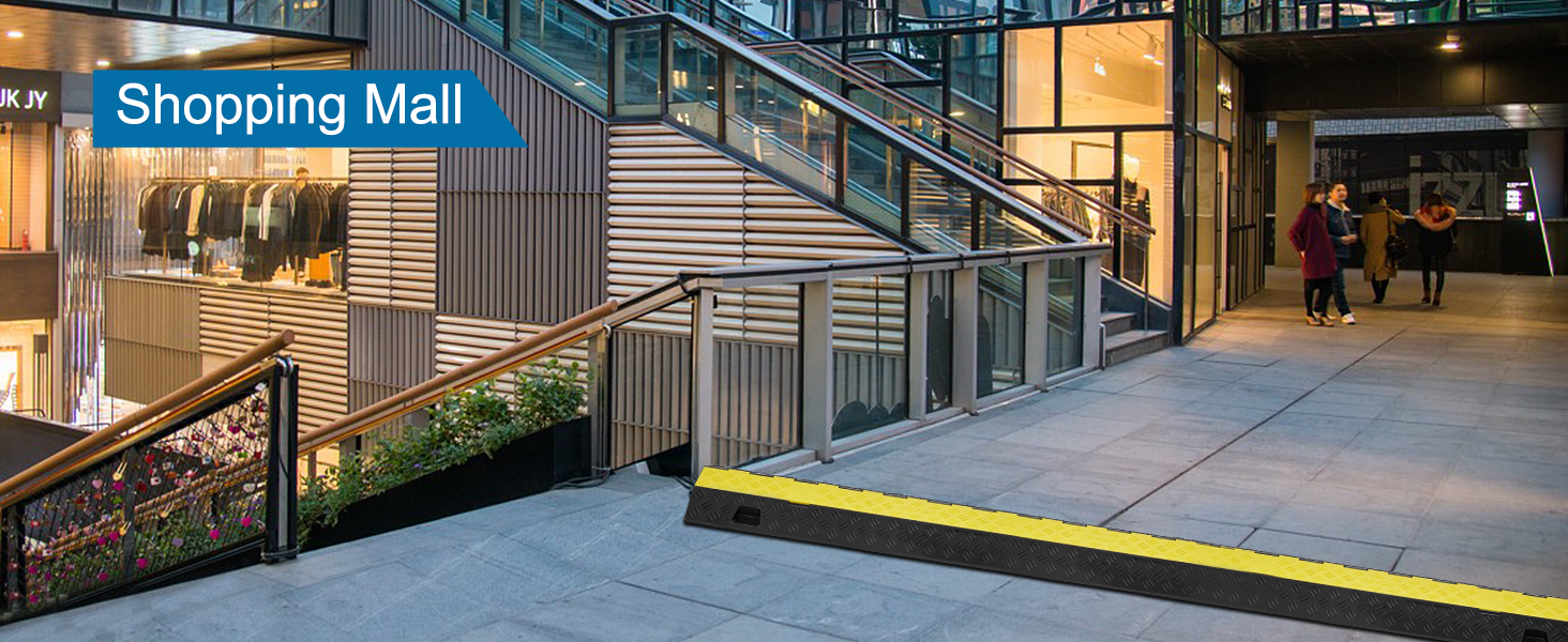 VEVOR kabeļu aizsargrampa pie iepirkšanās centra ieejas ar kāpnēm un mazumtirdzniecības veikalu fonā.