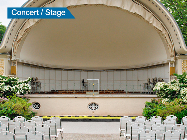 Koncertzāle ar baltiem krēsliem un VEVOR kabeļu aizsargrampu dārza norises vietā.