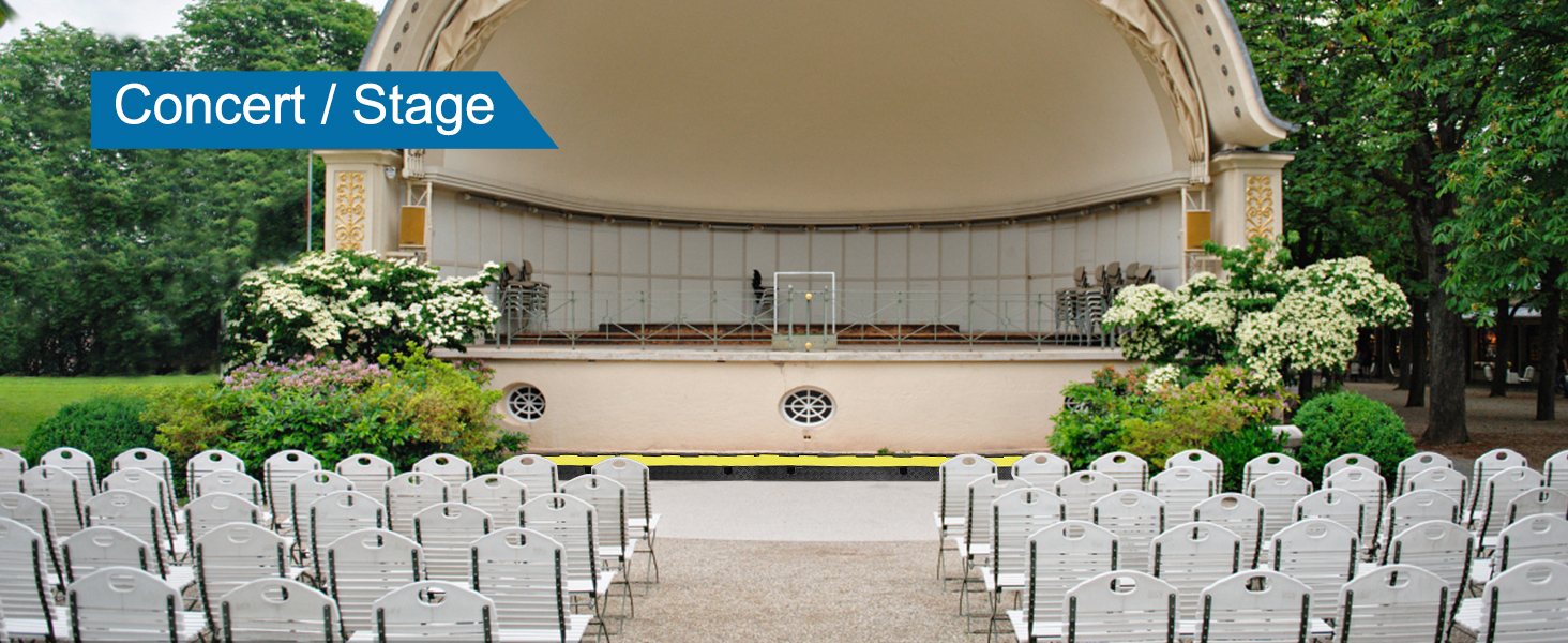 Koncertzāle ar baltiem krēsliem un VEVOR kabeļu aizsargrampu dārza norises vietā.