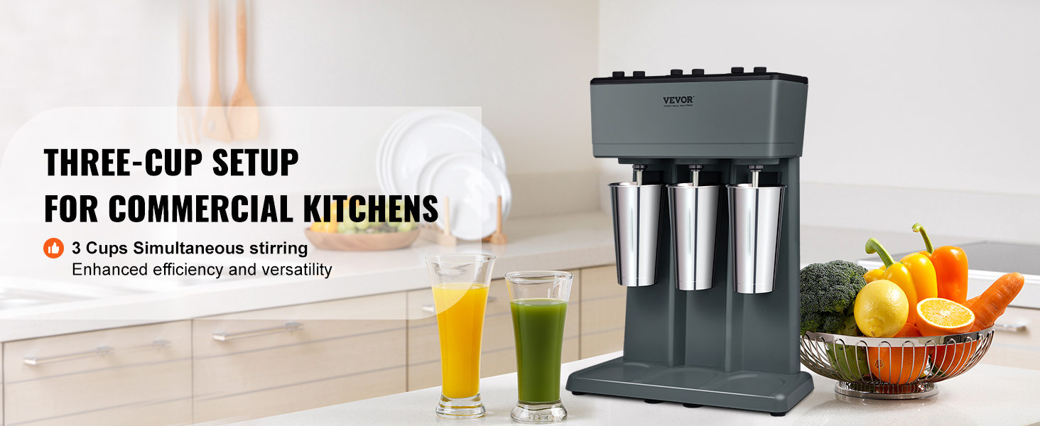 VEVOR milkshake maker in a kitchen with three stainless steel cups and fresh vegetables on the counter.