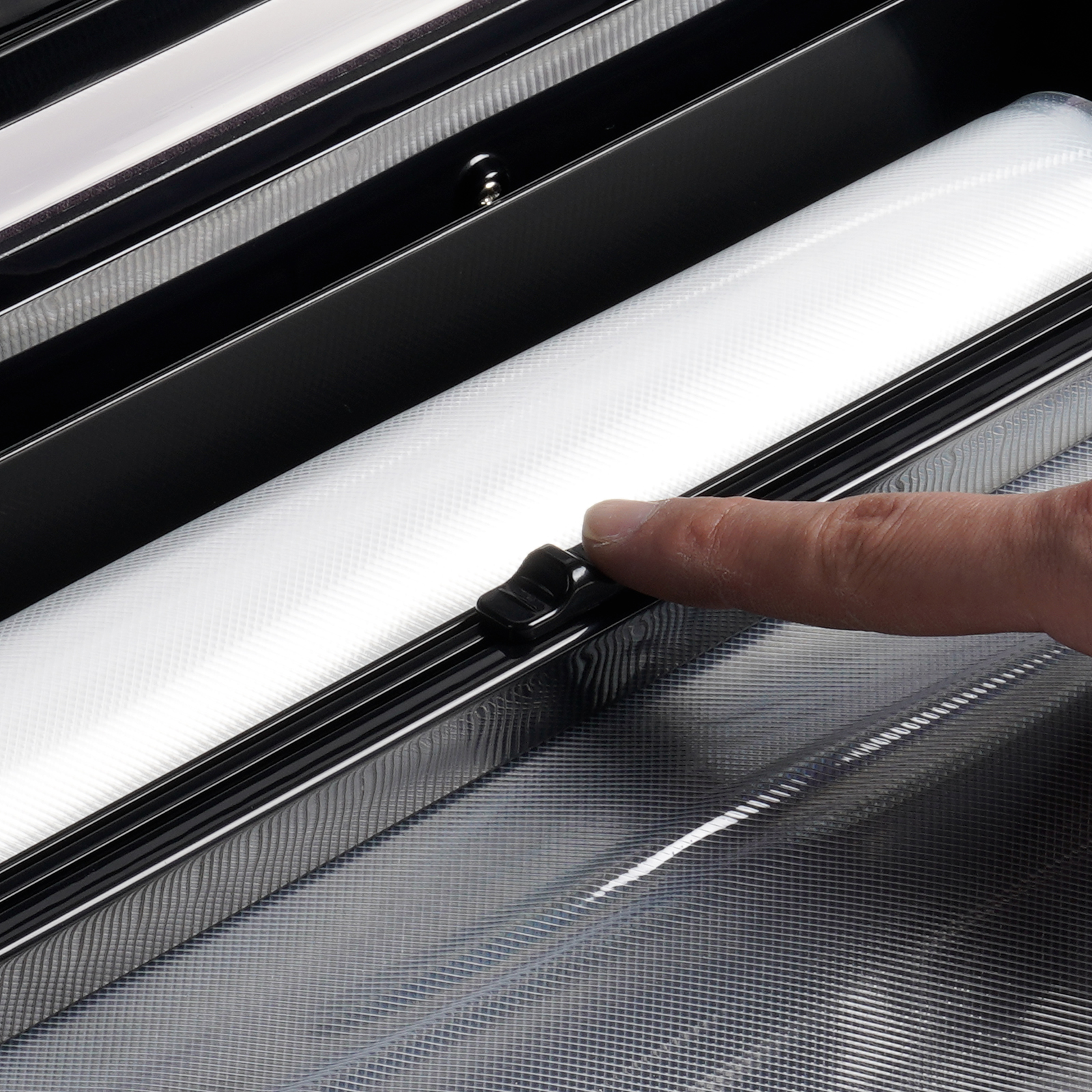 hand pressing a button on the VEVOR vacuum sealer with sealing bags and machine spout visible.