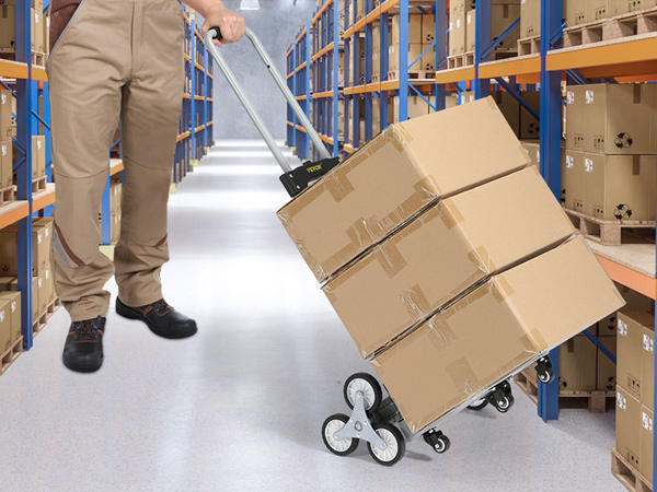 warehouse worker using VEVOR stair climbing cart to move stacked boxes between shelves.