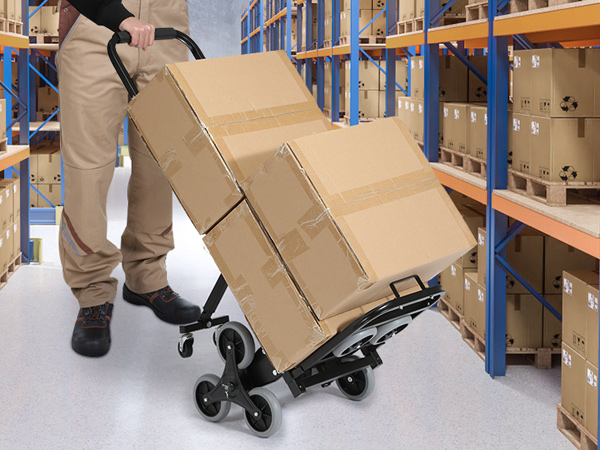 warehouse worker using VEVOR stair climbing hand truck to move cardboard boxes between shelves.