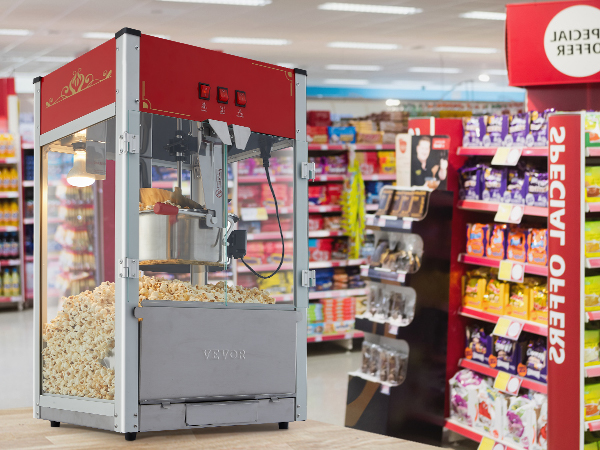 Машина для приготовления попкорна VEVOR в оживленном ряду супермаркета, где представлены закуски и специальные предложения.