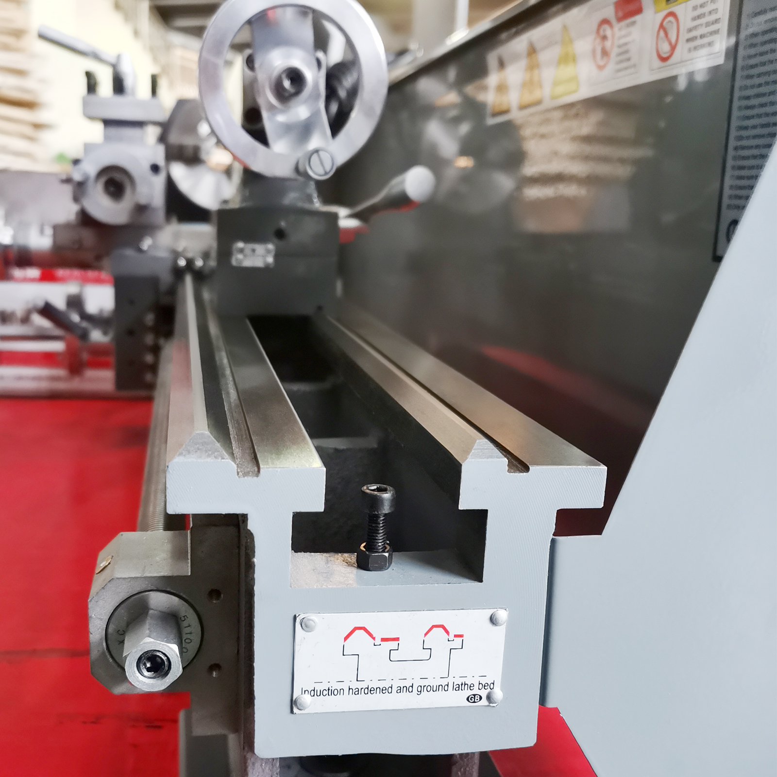 VEVOR metal lathe with precision bed, hardened and ground for accuracy, against a red industrial background.