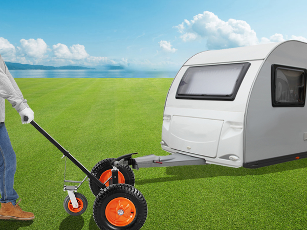 Cilvēks izmanto VEVOR piekabes ratiņus, lai manevrētu lielu baltu piekabi pa zāļainu lauku.