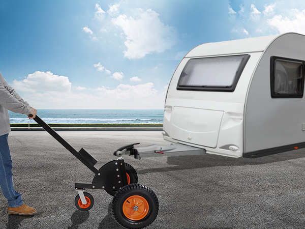 Vīrietis izmanto VEVOR piekabes ratiņus, lai manevrētu lielu baltu dzīvojamo piekabi netālu no piejūras ceļa.